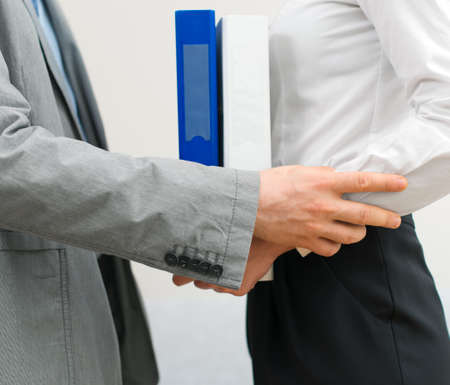 Sexual harassment at work. Man flirting with woman in office.の写真素材