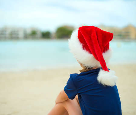 Little girl sitting on the beach. Christmas and new year vacations concept.の写真素材