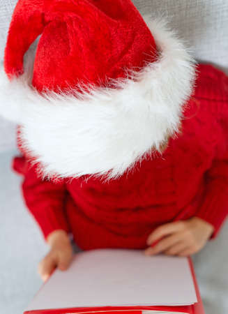 Little girl in red hat writing a letter to Santa Claus. Top view.の写真素材