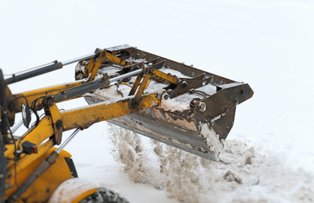 Tractor shoveling snow on the street.