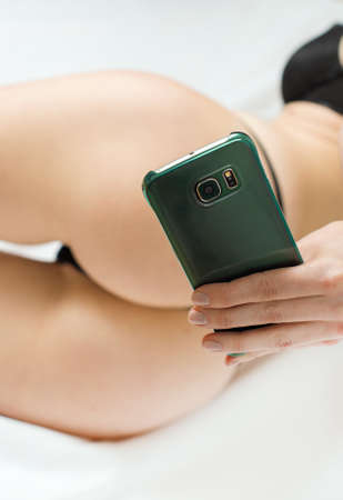 Woman taking sexual photo of herself with mobile phone.の写真素材