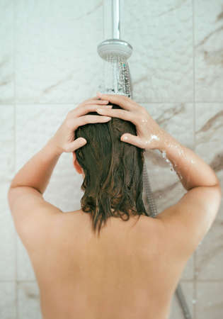 Woman is taking shower. Back view.の写真素材