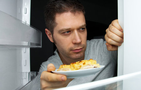 Man taking food out of refrigerator at night.