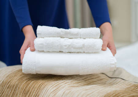 Room service. Woman changing towels in hotel room.の写真素材