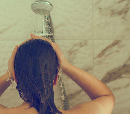 Woman is taking shower. Back view. Place for text.の写真素材