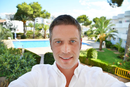 Happy man photographing himself on the balcony of his hotel on vacation.