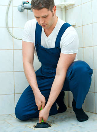 Plumber repairing bathroom with hand plunger.の写真素材