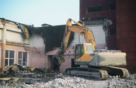 Hydraulic demolition crane dismantling school building.の写真素材