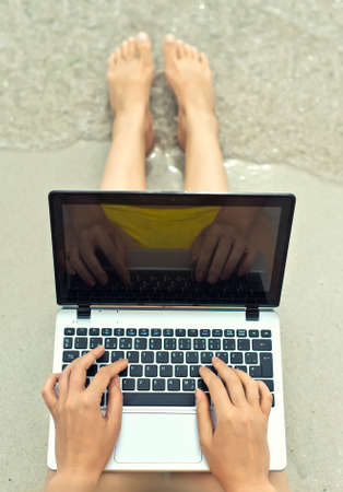 Girl working on laptop on the beach. Top view.の写真素材