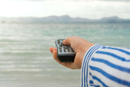 Magic remote control. Image that you can choose anything you want, for example your vacations near the sea.の写真素材