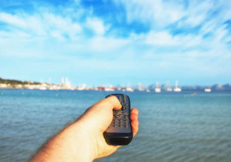 Magic remote control. Image that you can choose anything you want, for example your vacations near the sea.の写真素材