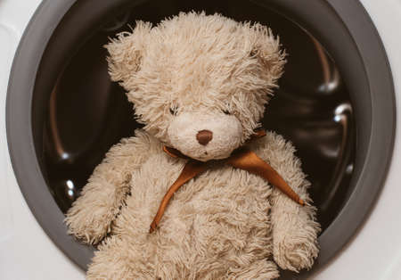 Plush bear sitting on washing machine.の写真素材