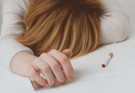 Drunk woman sleeping on the table. Female alcoholism.の写真素材