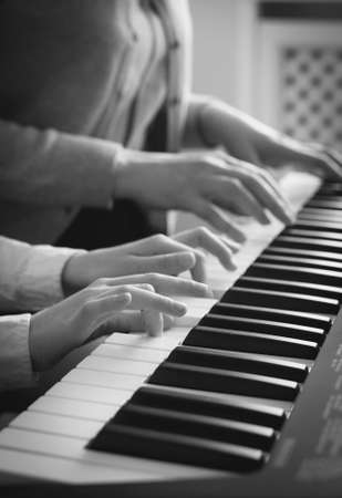 Woman teaching little girl to play the piano. BW Photo.の写真素材