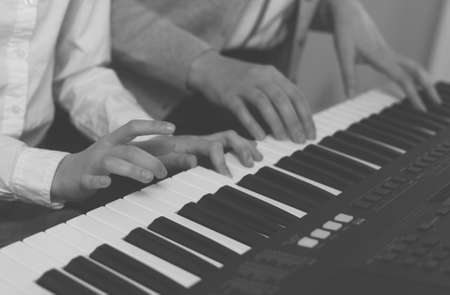 Woman teaching little girl to play the piano. BW Photo.の写真素材