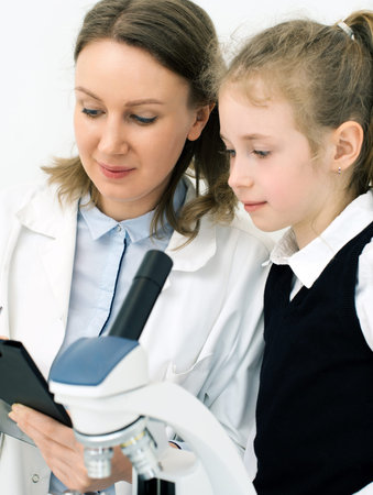 Woman and little girl using microscope in laboratory.