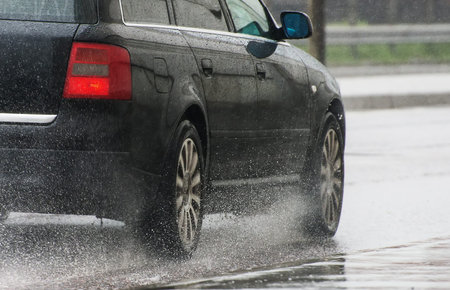 Car riding down the street in the rain.の写真素材