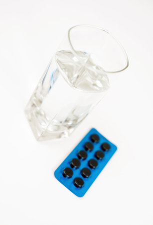 Activated carbon pills and glass of water.