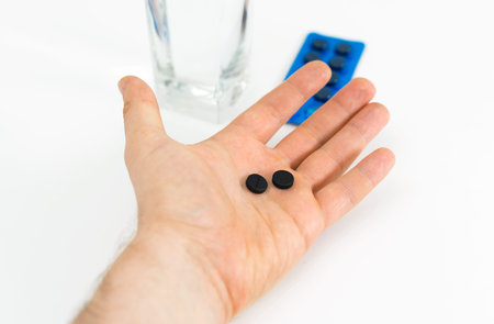 Man's hand holding activated carbon pills.の写真素材