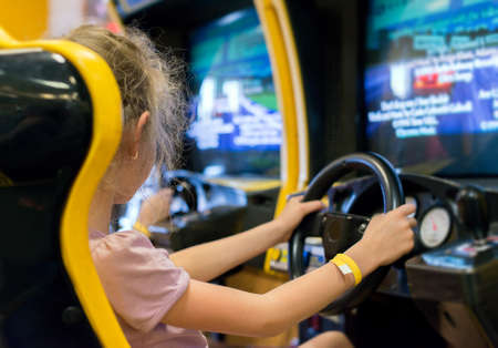 Little girl playing racing simulator game in theme park.の写真素材