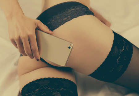 Woman taking sexual photo of herself with mobile phone.の写真素材