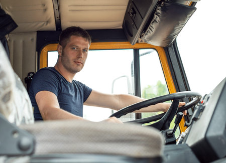 Male trucker in cabin of his yellow truck.