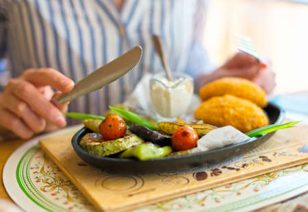Woman eating two Chicken Kiev with fried vegetables.の写真素材