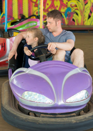 Father and daughter having fun on bumper car in amusement park.のeditorial素材