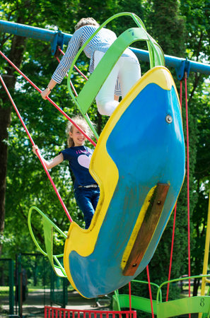 Little girl and her mother having fun on standing swings.