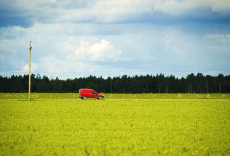 Red car traveling along the country road.の写真素材