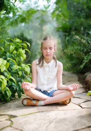Cute little girl meditating in the garden.の写真素材