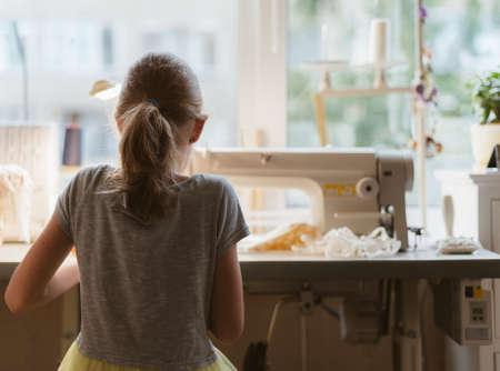 Little girl working on sewing machine at home.の写真素材