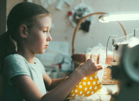 Little girl working on sewing machine at home.の写真素材