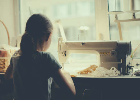 Little girl working on sewing machine at home.の写真素材