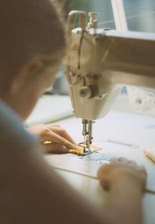 Little girl working on sewing machine at home. Close-up view.の写真素材