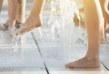 Woman having fun in small fountains at hot summer.
