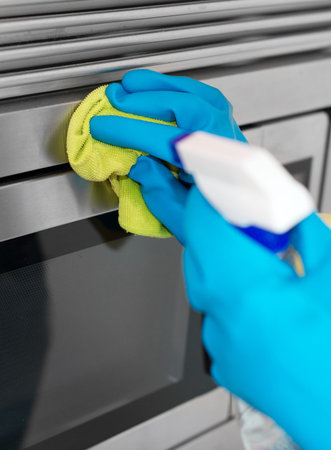 House cleaning. Woman is wiping microwave oven.の写真素材