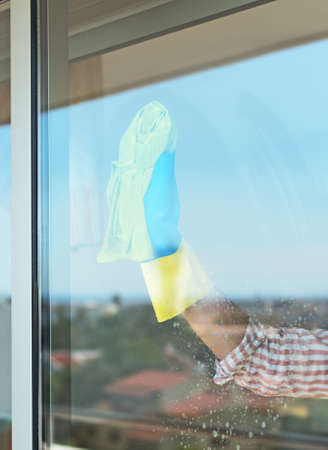 House cleaning. Woman is wiping glass on the balcony.の写真素材