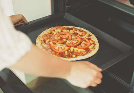 Woman preparing homemade pizza in oven.の写真素材