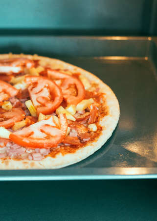 Homemade pizza with tomatoes in oven.の写真素材