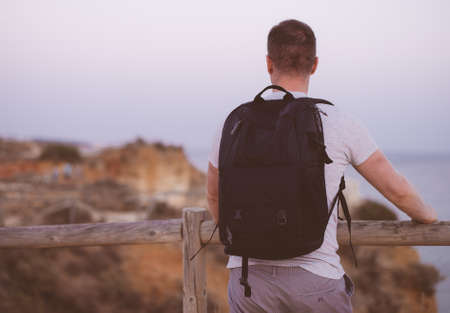 Male tourist with backpack looking at the ocean.の写真素材