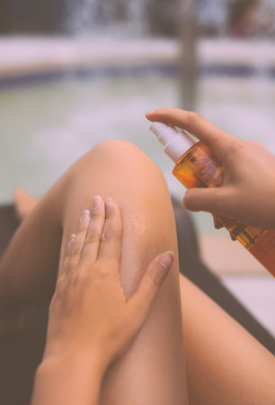 Woman applying sunblock cream on her legs.