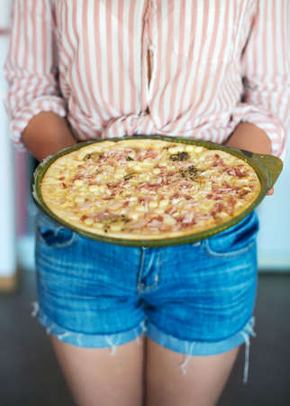 Woman holding pizza bought in a store.の写真素材