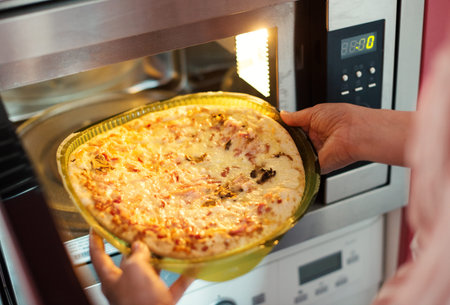 Woman preparing pizza bought in a store.