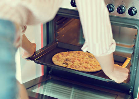 Woman preparing pizza bought in a store.の写真素材