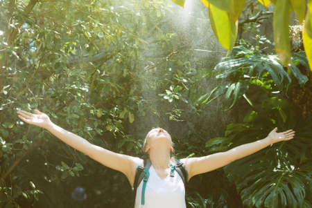 Female tourist with backpack under the rain in jungle.の写真素材