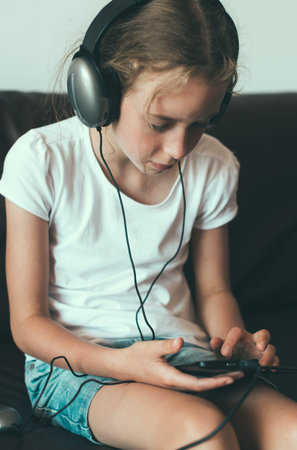 Little girl listening to the music on the phone.