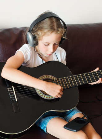 Little girl with headphones playing the guitar.の写真素材