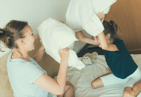 Mother and daughter fighting by pillows.の写真素材