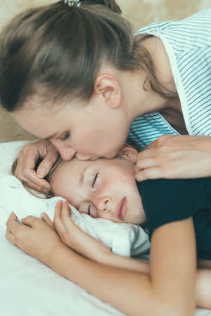 Mom kisses her daughter before going to bed.の写真素材